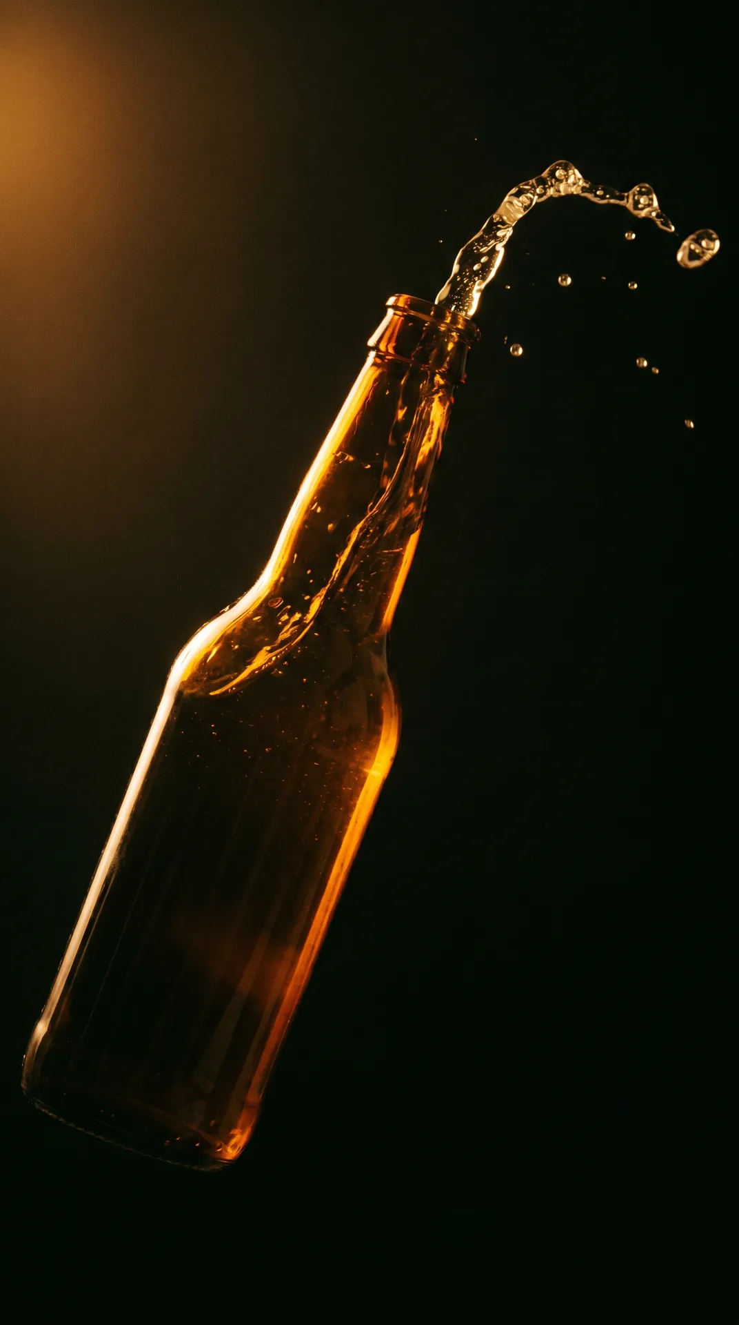 Vertikales Still einer Amber-Glasflasche im Pour-Moment vor schwarzem Hintergrund.